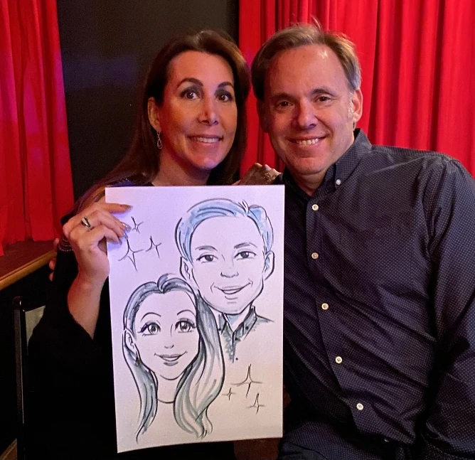 A couple holding their hand-drawn anime-style caricature on paper