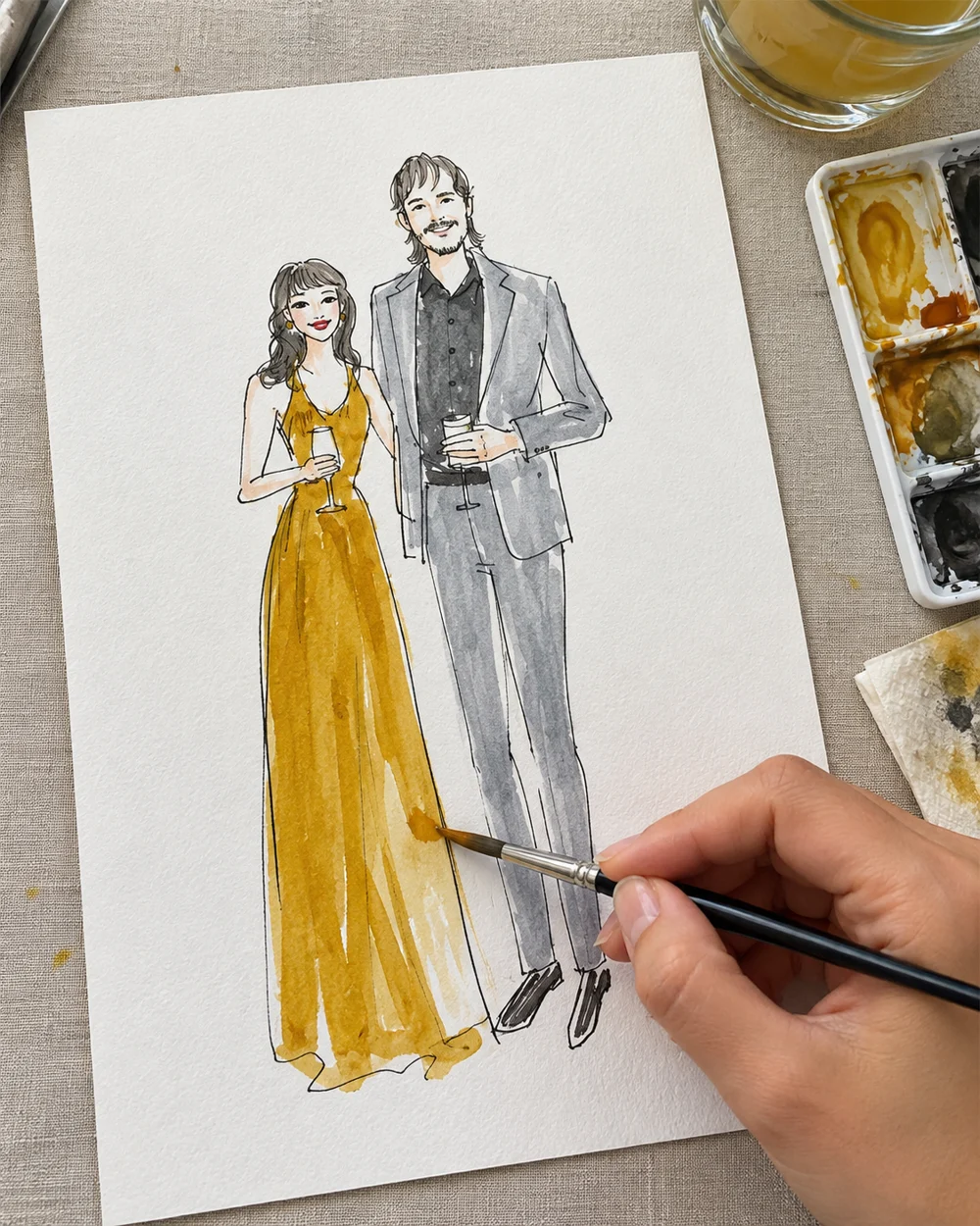 Artist painting a couple’s fashion sketch in watercolor