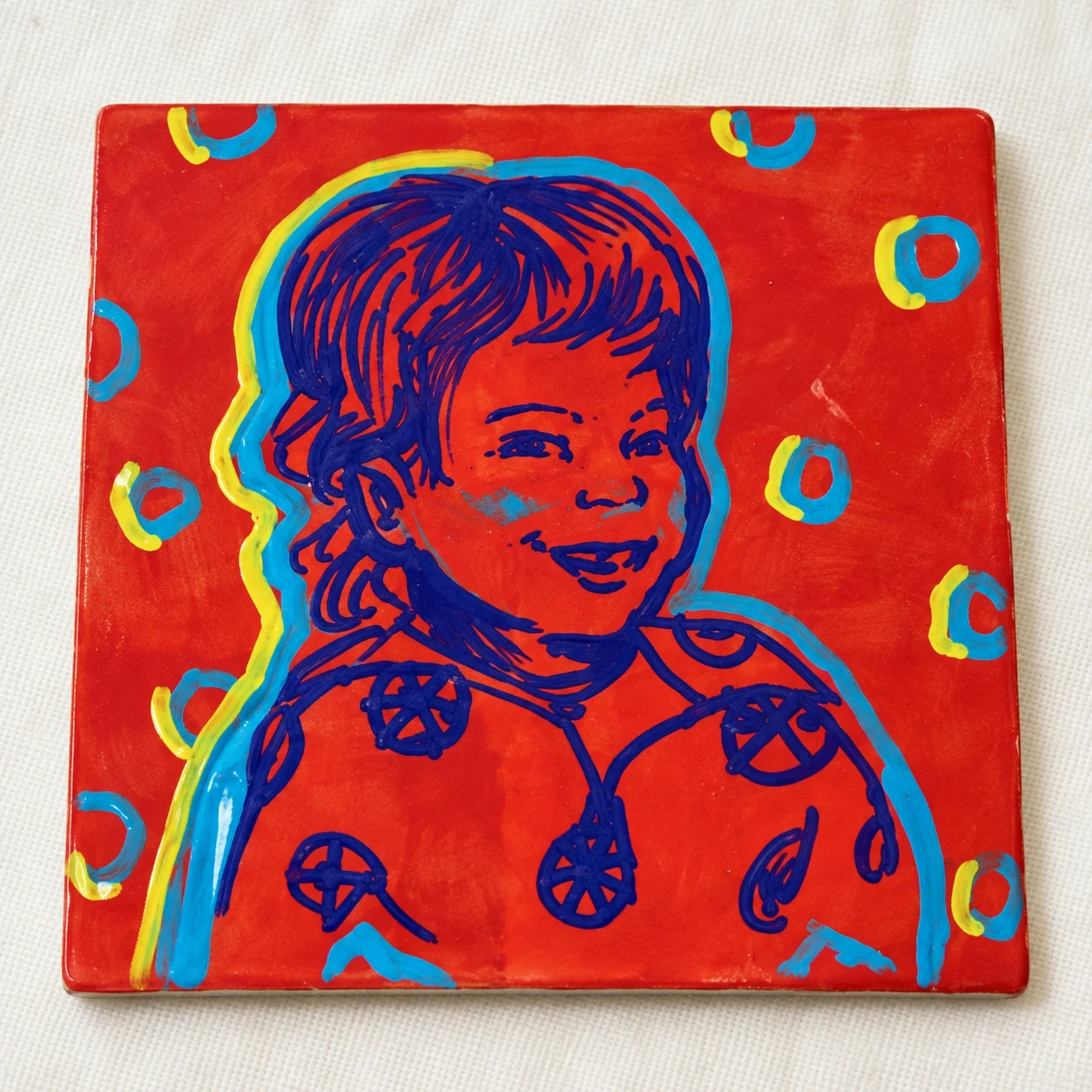 Child portrait painted on a bright red pop art tile